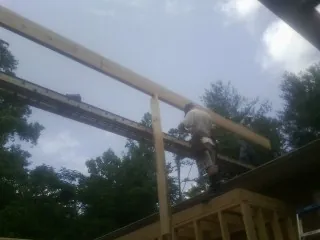 Carpenter setting a ridge beam over a new addition frame — Ice Dam Removal by Roofing Brothers in Gulfport