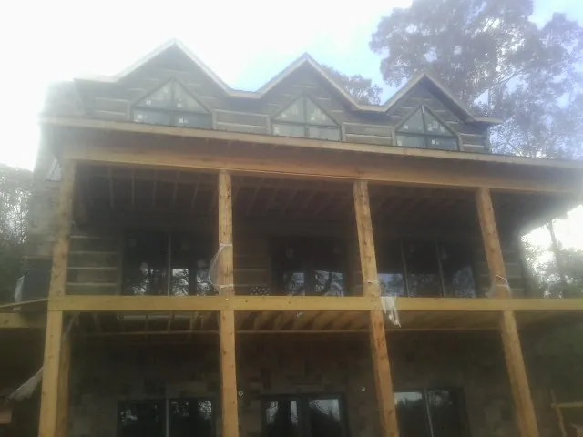 Dormers and porch framing on a large log home under construction — Roof Coating work by our crew in Gulfport