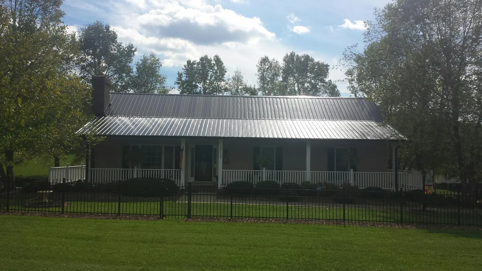 Gray metal roof on a brick ranch with a full width front porch — Gutter Guard Installation work by our crew in Gulfport