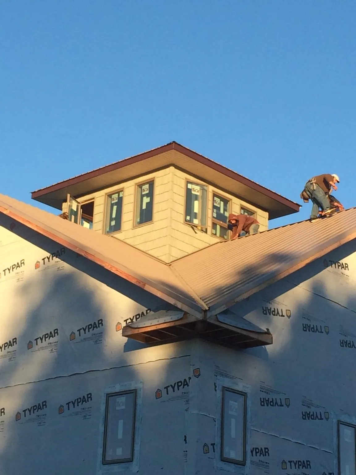 Roofers working around a rooftop cupola on a new metal roof at sunset — Roof Waterproofing in Gulfport by Roofing Brothers